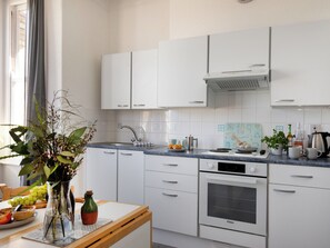 Et moderne køkken med hvide skabe, en indbygget ovn og en bordplade med forskellige køkkenredskaber.