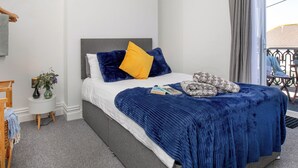 A neatly arranged bedroom with a bed, bedside tables, a small plant, and a view of the outside. - A comfortable first-floor apartment for two with lovely sea views. (Paignton)