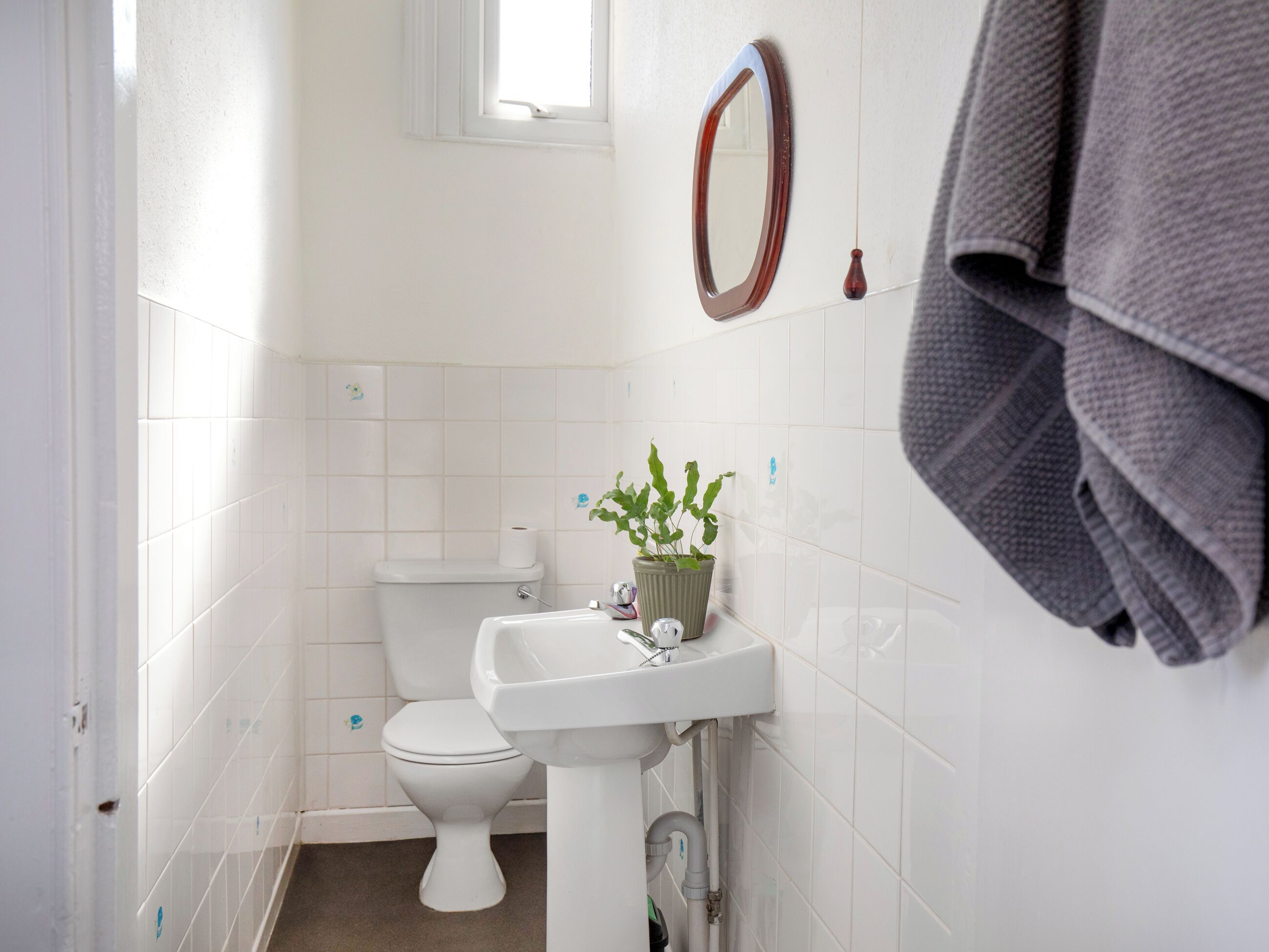 A bathroom with a toilet, sink, and a mirror.