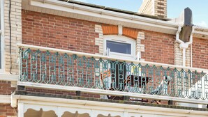 A brick building with a balcony featuring ornate metal railings.