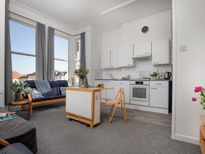 A modern apartment with a living area, kitchenette, and large windows. - A comfortable first-floor apartment for two with lovely sea views. (Paignton)