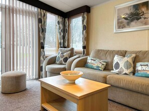 A living room with a sofa, ottoman, and a coffee table with a bowl. - 2 bedroom accommodation in Angus (Edinburgh and the Lothians)