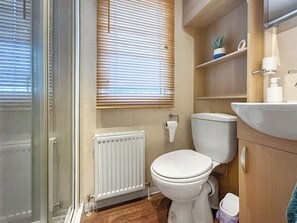 A bathroom with a toilet, a radiator, a window with blinds, a shelf with a plant, and a sink with toiletries. - 2 bedroom accommodation in Angus (Edinburgh and the Lothians)