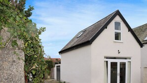 Een gelijkvloers huis met schuin dak, voordeur en garage.
