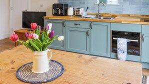 Een keuken met blauwgroene kastjes, een houten aanrecht, een koffiezetapparaat, een broodrooster en een spoelbak.