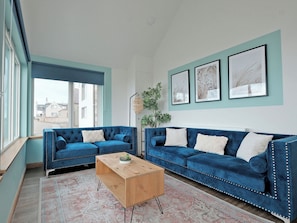 A living room with two blue sofas, a wooden coffee table, and a patterned rug. - 4 bedroom accommodation in Portknockie (Portknockie)