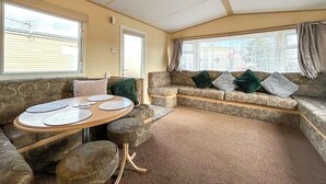 A cozy interior with a stone bench, a round table with plates, and a window with curtains.