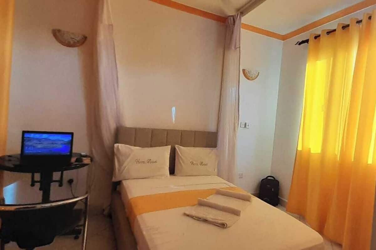 Ein Hotelzimmer mit einem Bett, einem Schreibtisch mit Computer und Vorhängen.