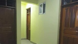 Un pasillo con suelo de baldosas, puertas de madera y un ventanal pequeño.