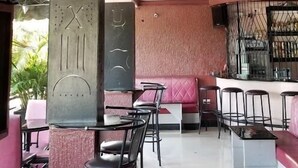 Un interior moderno con una zona de bar, asientos y una pared decorativa con un reloj.