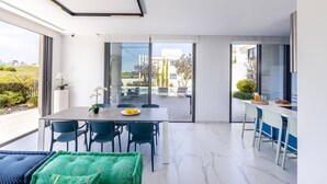 Un espace repas moderne comprenant une table, des chaises et donnant sur la terrasse extérieure.