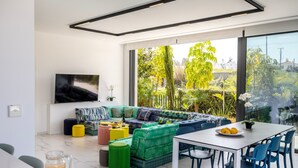 Una sala de estar moderna con un gran ventanal, un sofá, una mesa de comedor y un televisor.