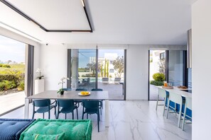 A modern dining area with a table, chairs, and a view of the outdoor patio. - Protaras By the Bay Villa 19 (Paralimni)