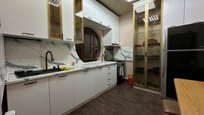 Une cuisine moderne dotée de plans de travail en marbre, d’un réfrigérateur en acier inoxydable et d’armoires encastrées.