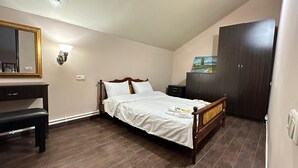 Une chambre à coucher avec un lit en bois, un bureau, une chaise, une armoire et un tableau accroché au mur.