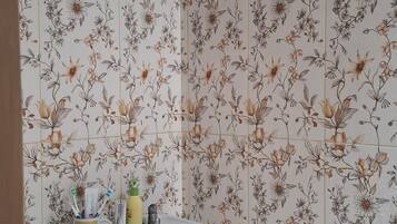 Une salle de bain avec des carreaux à motifs floraux, un lavabo blanc et des articles de toilette posés sur le comptoir.