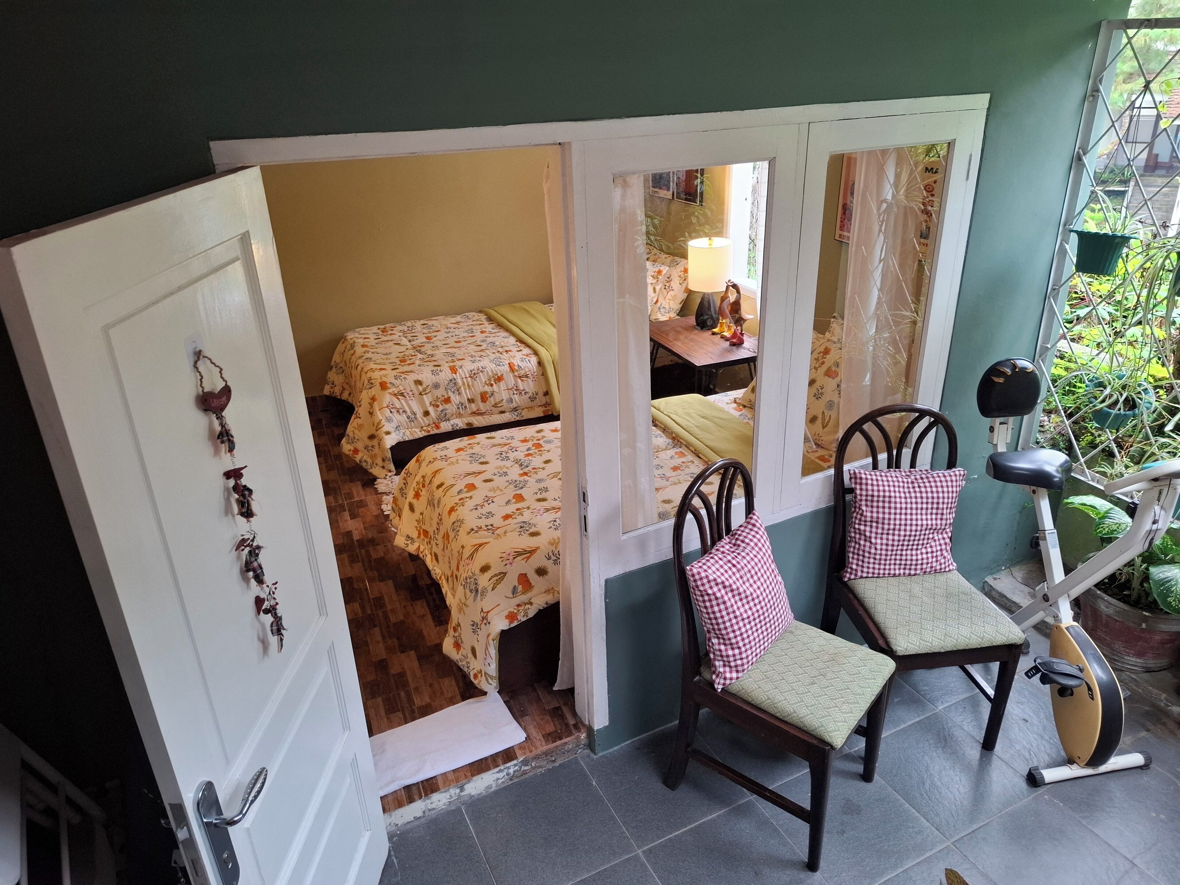 A room with two beds, a chair, a small table, and a bicycle.