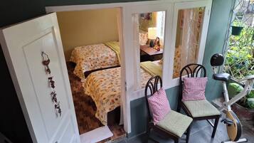 A room with two beds, a chair, a small table, and a bicycle.