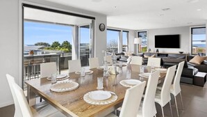 Un comedor moderno con una gran mesa de madera dispuesta para seis personas, rodeada de sillas blancas.