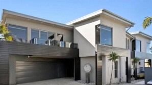 Una casa moderna de dos pisos con garaje, ventanas amplias y un balcón.