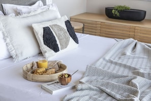 A neatly made bed with pillows, a bedside table with a book and a glass of orange juice, and a tray with pastries and a bowl of nuts. - Seafront Villa Gaione, Divine Sea Views, Private Infinity Pool, Furnished. (Crete)