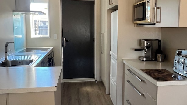 A modern kitchen with stainless steel appliances, a black door, and a view of the outside. - Modern 2BR St Albans Near CBD, Stadium & The Palms mall (Christchurch)