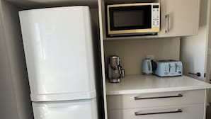 A compact kitchen with a white refrigerator, a microwave, a toaster, and a coffee maker. - Modern 2BR St Albans Near CBD, Stadium & The Palms mall (Christchurch)
