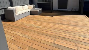 A wooden deck with a sofa and cushions, a door, and a window. - Modern 2BR St Albans Near CBD, Stadium & The Palms mall (Christchurch)