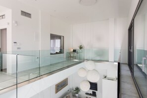 A modern interior with a glass railing, a flat-screen TV, and a potted plant. - Villa Philaea, Divine Sea Views, Private Infinity Pool, Furnished Terrace,. (Crete)