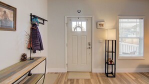 A hallway with a white door, a bench with a coat rack, a small shelf with a lamp, and a window with blinds. - Mt. Princeton Views. Remodeled. Fire Pit & BBQ (Buena Vista)