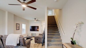 A living room with a grey sofa, a coffee table, and a TV. There is a staircase with a wooden railing leading to an upper floor. - Mt. Princeton Views. Remodeled. Fire Pit & BBQ (Buena Vista)