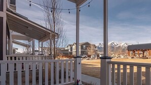 A covered porch with a white railing, a wooden pergola, and a view of a residential area with houses and mountains in the background. - Mt. Princeton Views. Remodeled. Fire Pit & BBQ (Buena Vista)