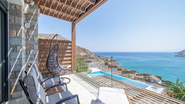 Ein Balkon mit Meerblick, einem Pool und Sitzgelegenheiten im Freien.