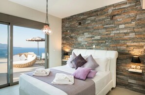 Ein modernes Schlafzimmer mit Steinwand, einem großen Bett und Meerblick.