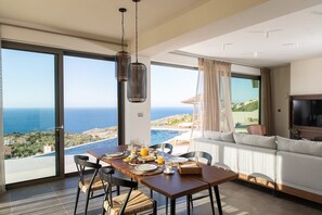 Uma área de refeições com mesa posta para o café da manhã, com vista para um mar panorâmico.