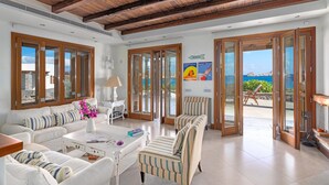 A spacious living room with a high ceiling, large windows, and a view of the sea. - Seafront Villa Solaryth, Divine Sea Views, Private Pool, Furnished Terrace,. (Crete)