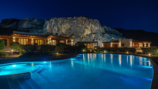 A luxurious hotel with a swimming pool, a mountain backdrop, and well-lit outdoor areas. - Seafront Villa Solaryth, Divine Sea Views, Private Pool, Furnished Terrace,. (Crete)