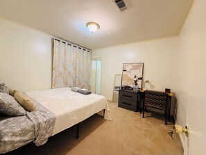 Ein Schlafzimmer mit einem Bett, einem Schminktisch, einem Spiegel und einer Tür.