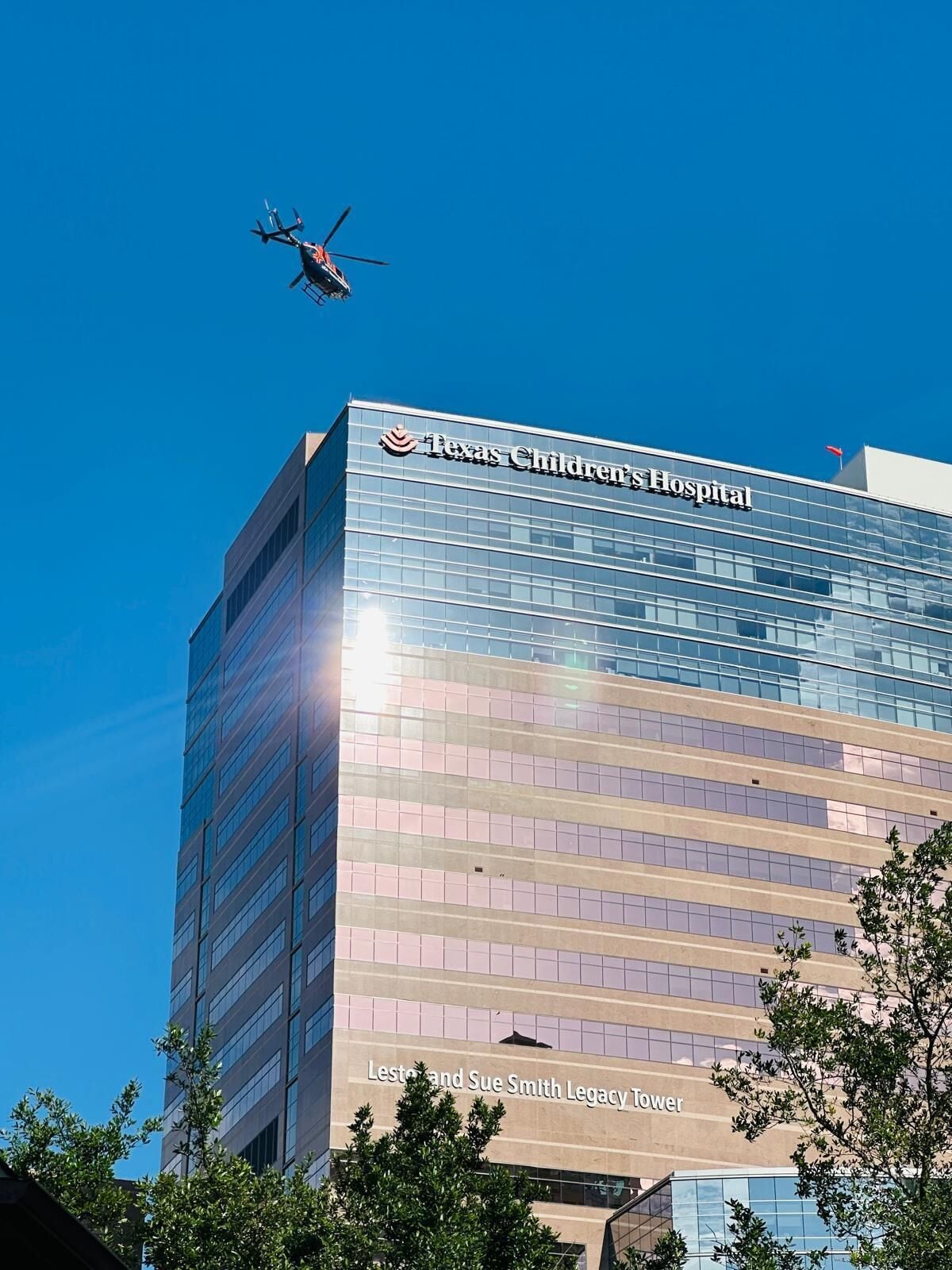 A modern building with a clear sky and a helicopter in flight.