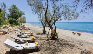 A beach with sun loungers and a table under a tree, overlooking the sea. - Villa Terrissa, Divine Sea Views, Private Pool, Furnished Terrace, Arvi (Crete)