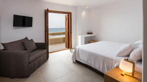 Une chambre avec un lit, un canapé, une télévision et une vue sur la plage.