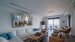 A modern living room with a large mirror, white sofas, a wooden coffee table, and leather armchairs. - Seafront Villa Astraiax, Divine Sea Views, Private Infinity Pool, Furnished. (Crete)