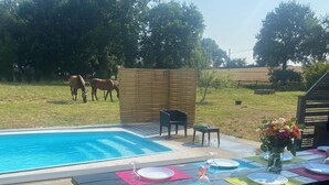 A poolside area with a wooden deck, picnic table, and chairs.