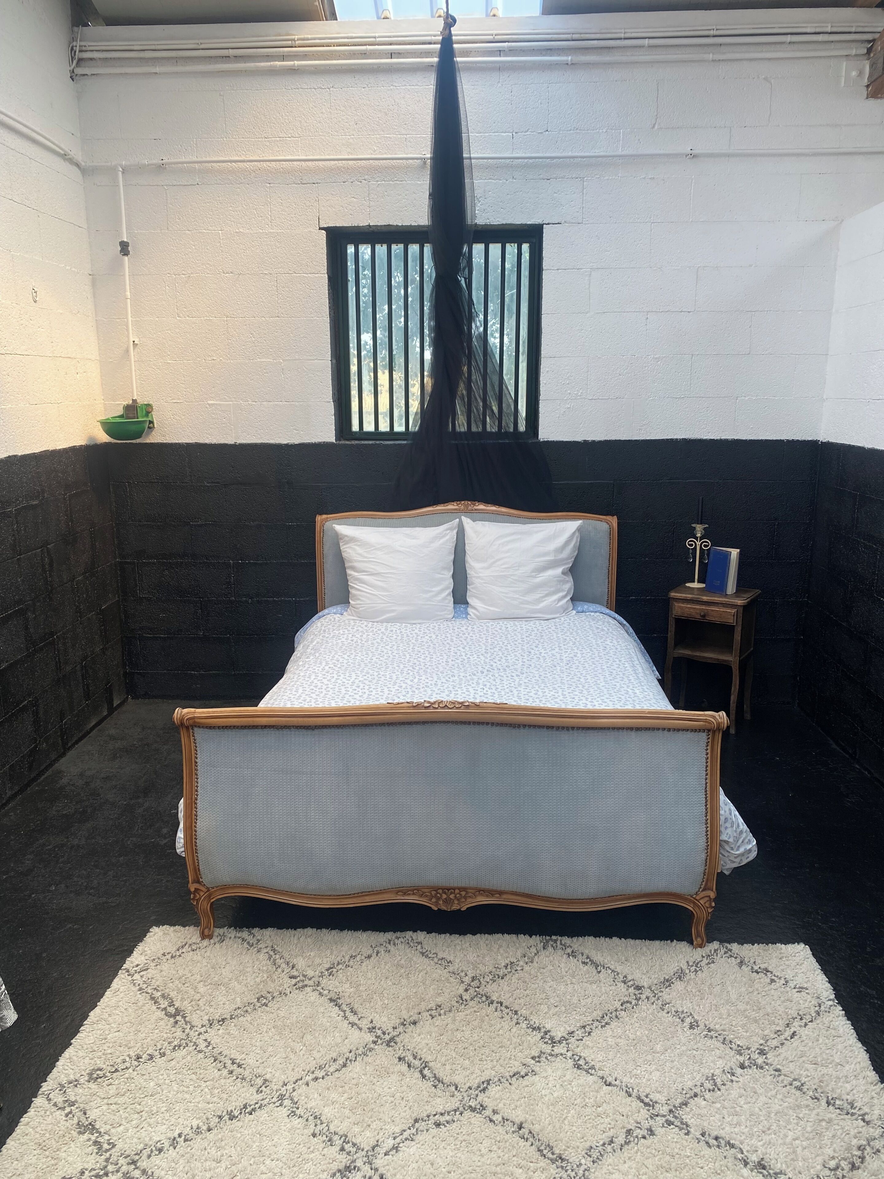 A room with a bed, a window, and a nightstand.