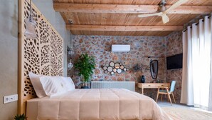 Ein Schlafzimmer mit Bett, Holzboden, Heizkörper, Schreibtisch, Stuhl und einer Pflanze.
