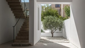 A modern interior with a concrete staircase, a small tree, and a view of buildings outside. - Seafront Villa Noctessa, Divine Sea Views, Private Infinity Pool, Furnished. (Crete)