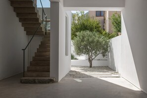 A modern interior with a concrete staircase, a small tree, and a view of buildings outside. - Seafront Villa Noctessa, Divine Sea Views, Private Infinity Pool, Furnished. (Crete)