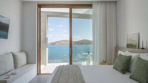 A hotel room with a large bed, a sofa, a balcony with a view of the sea, and a painting on the wall. - Seafront Villa Noctessa, Divine Sea Views, Private Infinity Pool, Furnished. (Crete)