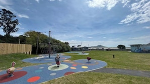Un parque infantil con círculos de colores en el suelo, una estructura para escalar y una zona vallada.