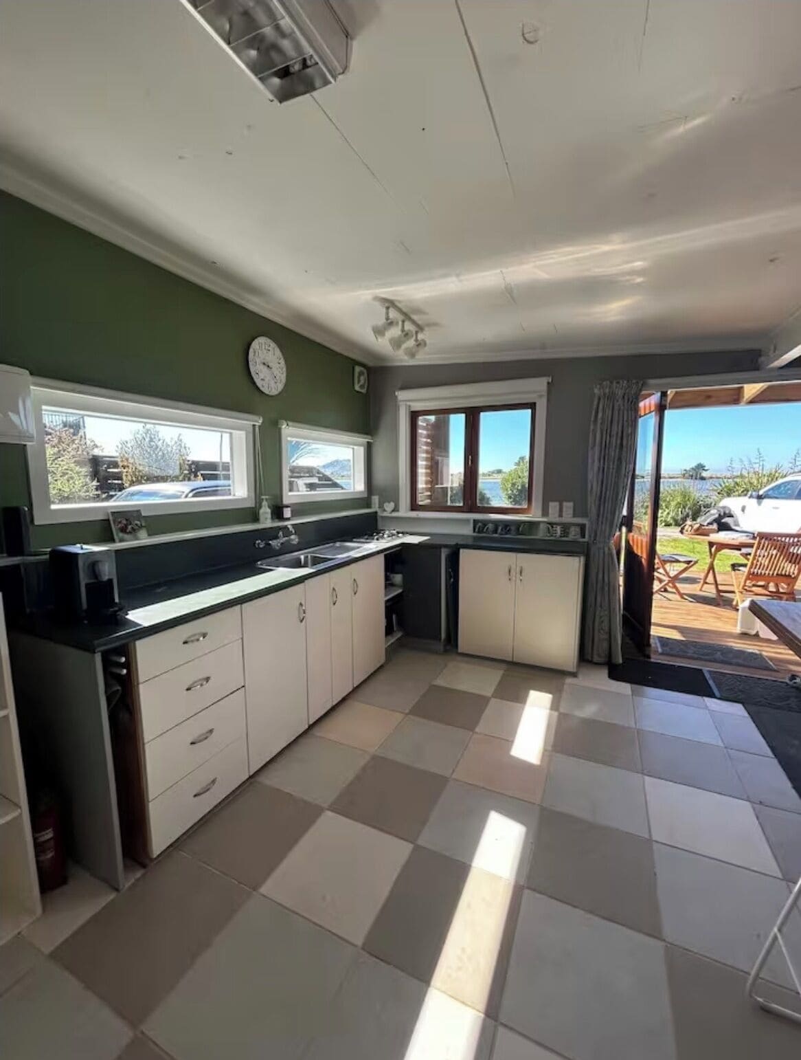 A kitchen with a large window, a clock, and a view of the outside.